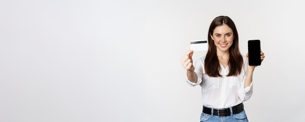 Foto gratuita retrato de modelo femenino que muestra la tarjeta de crédito con la pantalla del teléfono inteligente que recomienda la aplicación suplente