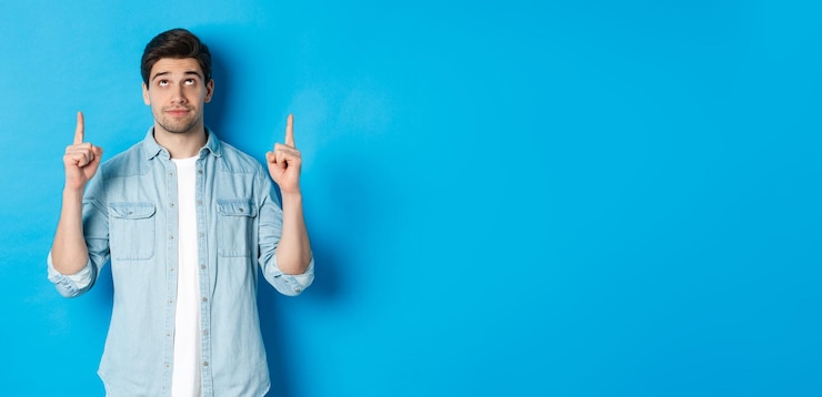 Foto gratuito retrato de modelo masculino disgustado y escéptico señalando con el dedo hacia arriba mirando algo desagradable