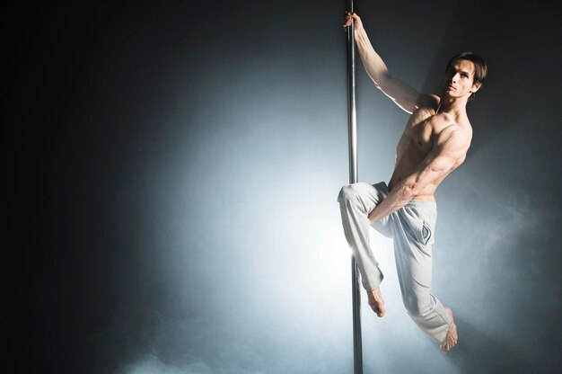 Retrato de modelo masculino fuerte realizando un pole dance