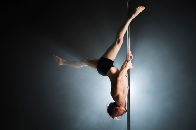 Retrato de modelo masculino fuerte realizando un pole dance