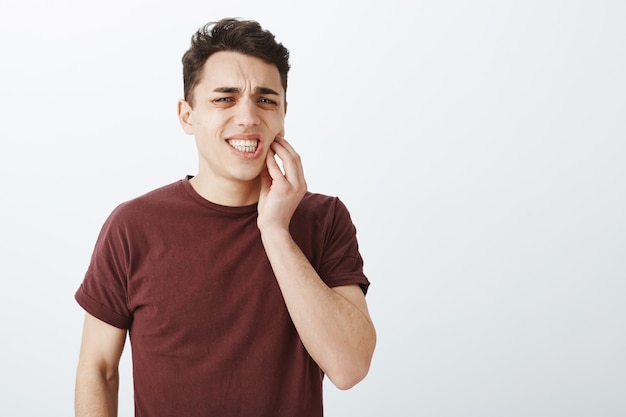 Retrato de modelo masculino joven sufrimiento disgustado en camiseta roja