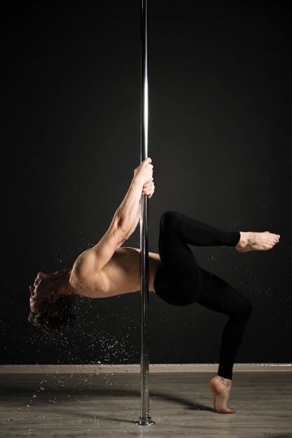 Retrato de modelo masculino profesional realizando un pole dance