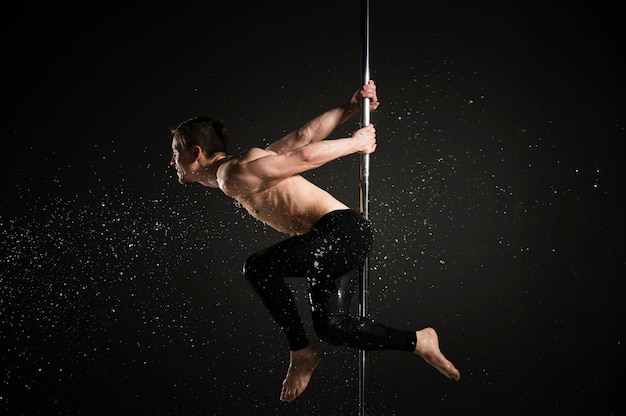 Retrato de modelo masculino profesional realizando un pole dance