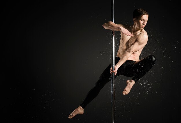 Retrato de modelo masculino profesional realizando un pole dance