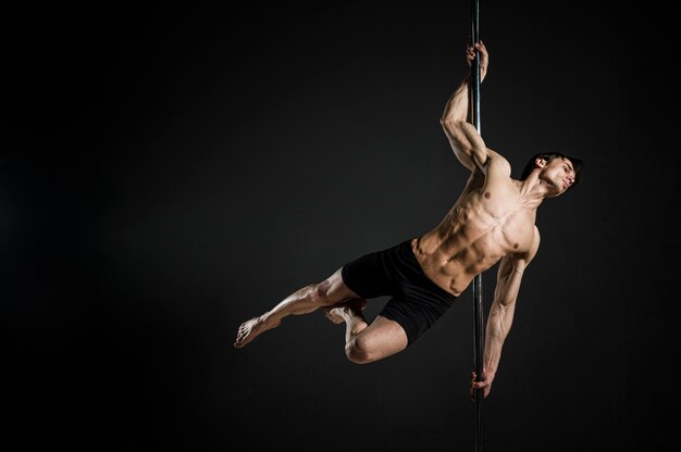 Retrato de modelo masculino realizando un pole dance