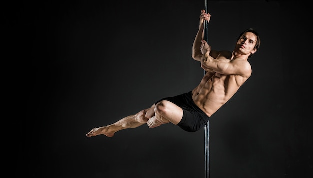 Retrato de modelo masculino realizando un pole dance