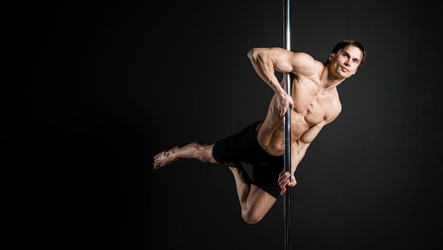 Retrato de modelo masculino realizando un pole dance