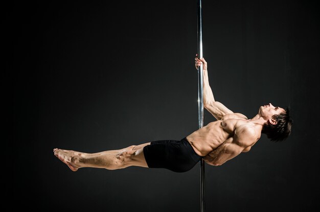 Retrato de modelo masculino realizando un pole dance