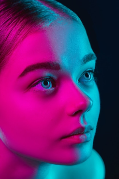 Retrato de modelo de moda femenina en luz de neón en estudio oscuro