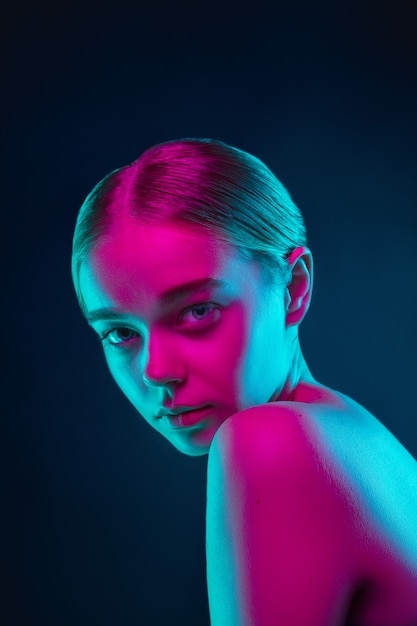 Retrato de modelo de moda femenina en luz de neón en estudio oscuro