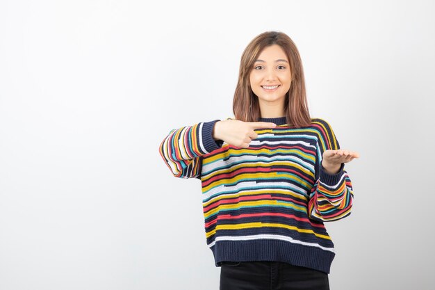 Retrato de un modelo de mujer joven apuntando a la mano.