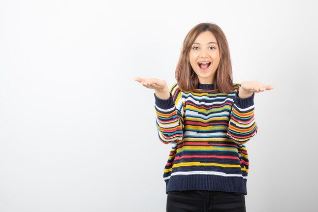 Retrato de un modelo de mujer joven sonriente que muestra las palmas abiertas.