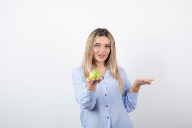 retrato de un modelo de niña bonita de pie y sosteniendo una manzana verde fresca.