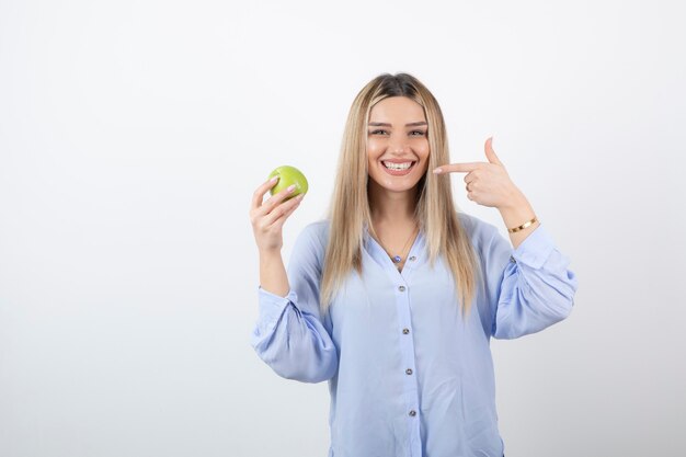 retrato de un modelo de niña bonita de pie y sosteniendo una manzana verde fresca.