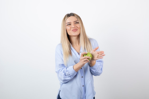 retrato de un modelo de niña bonita de pie y sosteniendo una manzana verde fresca.