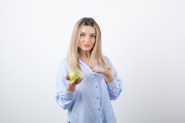 retrato de un modelo de niña bonita de pie y sosteniendo una manzana verde fresca.