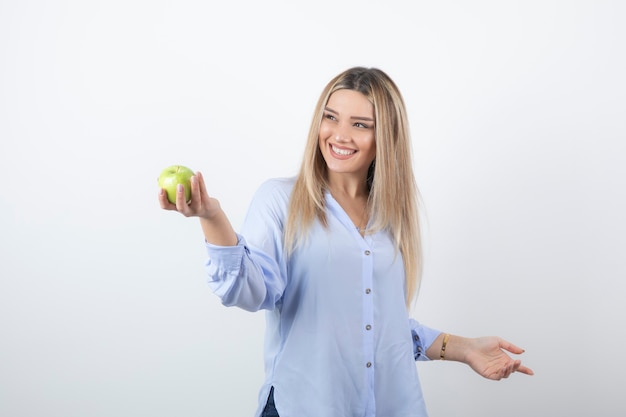 retrato de un modelo de niña bonita de pie y sosteniendo una manzana verde fresca.