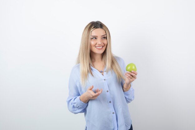 retrato de un modelo de niña bonita de pie y sosteniendo una manzana verde fresca.