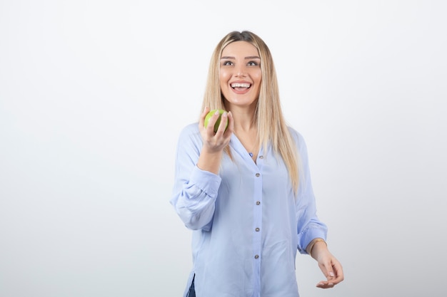 Foto gratuita retrato de un modelo de niña bonita de pie y sosteniendo una manzana verde fresca.