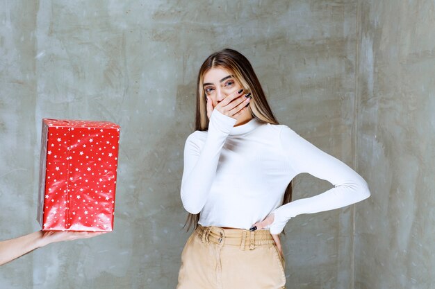 Retrato de un modelo de niña de pie cerca del cuadro actual aislado sobre piedra