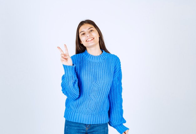 Retrato de un modelo de niña sonriente mostrando el signo de la victoria.