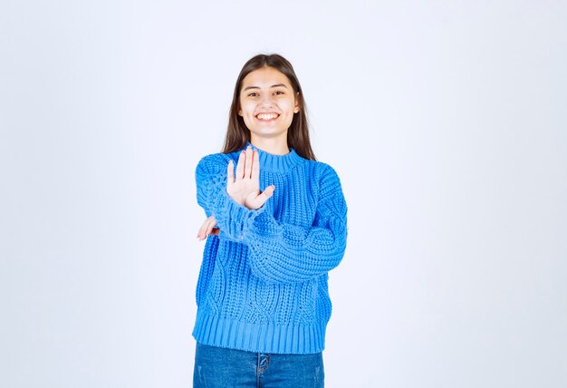 Retrato de un modelo de niña sonriente que muestra la señal de pare en blanco-gris.