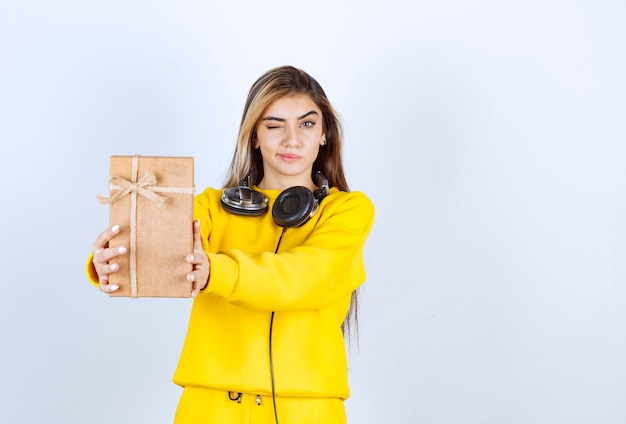 Retrato de un modelo de niña sosteniendo una caja de papel con arco aislado sobre pared blanca