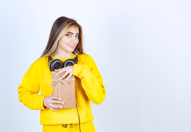 Retrato de un modelo de niña sosteniendo una caja de papel con arco aislado sobre pared blanca