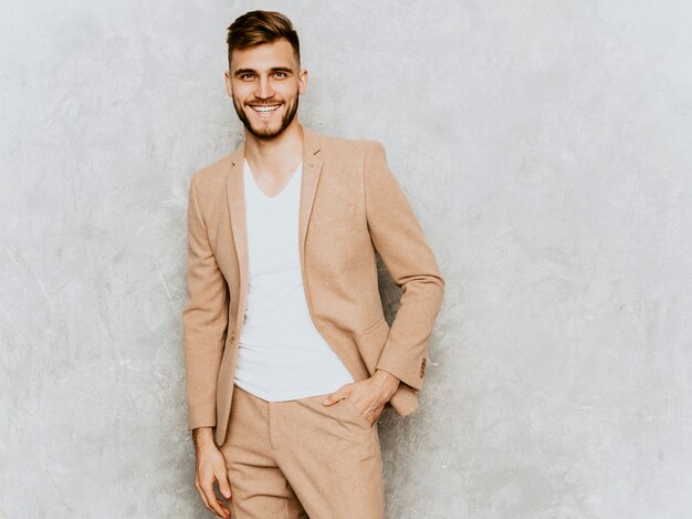 Retrato del modelo sonriente hermoso del hombre de negocios del inconformista que lleva el traje beige casual.