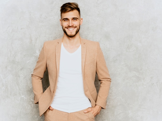 Retrato del modelo sonriente hermoso del hombre de negocios del inconformista que lleva el traje beige casual.