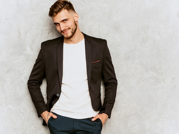 Retrato del modelo sonriente hermoso del hombre de negocios del inconformista que lleva el traje negro casual.