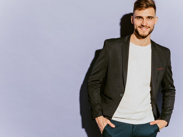 Retrato del modelo sonriente hermoso del hombre de negocios del inconformista que lleva el traje negro casual.