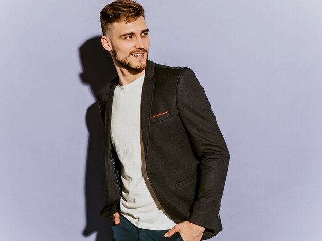 Retrato del modelo sonriente hermoso del hombre de negocios del inconformista que lleva el traje negro casual.