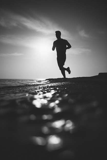 Foto gratuita retrato monocromático de un hombre corriendo en la playa