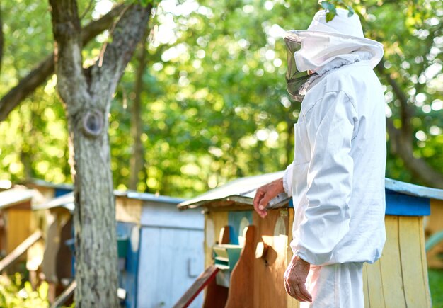 Retrato monocromático de un hombre mayor con traje de apicultura posando en su colmenar en el jardín copyspace profesión ocupación agricultor agricultura trabajo hobby estilo de vida concepto.