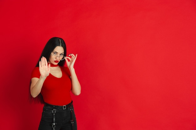 Foto gratuita retrato monocromo de mujer joven caucásica en pared roja emocional y expresiva