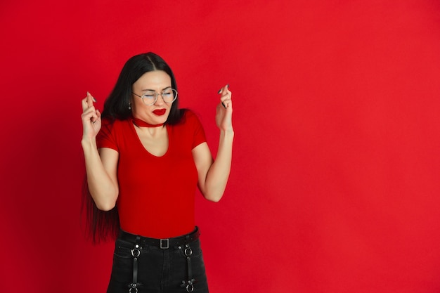 Foto gratuita retrato monocromo de mujer joven caucásica en pared roja emocional y expresiva