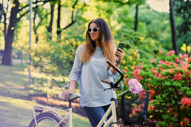 Retrato de morena con bicicleta de ciudad cerca del pabellón chino tradicional en un parque.