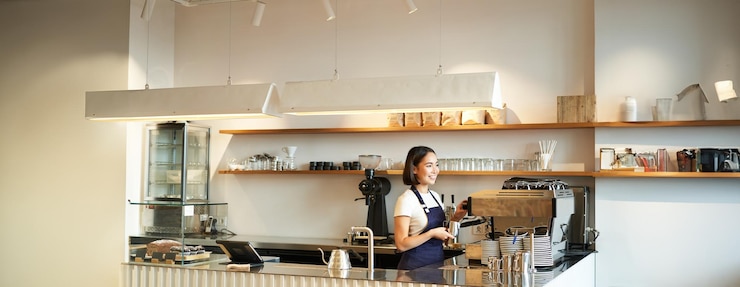 Foto gratuito retrato de un mostrador de café con una chica barista trabajando con una máquina de café haciendo pedidos para un cliente en