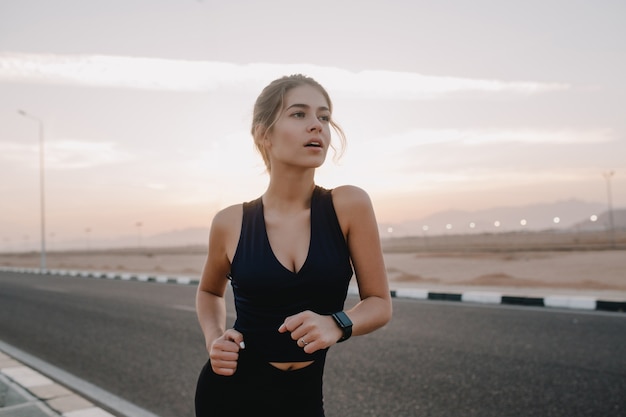 Retrato motivado a mujer increíble corriendo en la carretera en una mañana soleada. Entrenamiento, entrenamiento, expresando positividad, verdaderas emociones, estilo de vida saludable, trabajadora, deportista fuerte