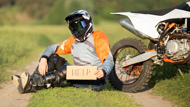 Retrato de motociclista con cartel de ayuda