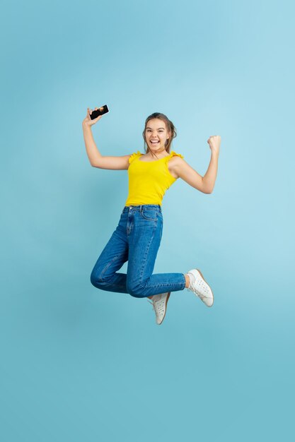 Retrato de la muchacha adolescente caucásica sobre fondo azul. Modelo de pelo largo hermoso en casual.