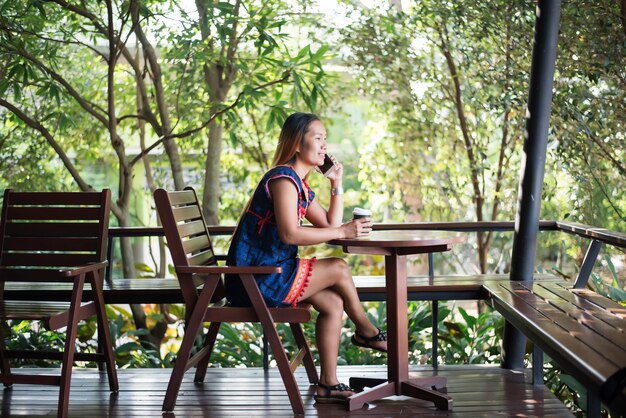 Retrato de muchacha asiática hermosa que usa su teléfono móvil en café.