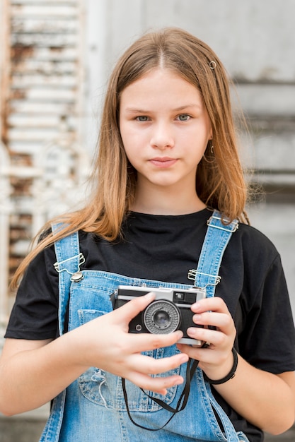 Foto gratuita retrato de la muchacha hermosa adolescente que sostiene la cámara retra