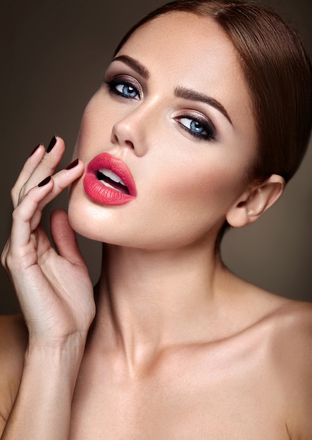 Retrato de muchacha hermosa modelo con maquillaje de noche y peinado romántico. Tocando sus labios rojos