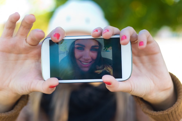Retrato de muchacha hermosa que toma un selfie con el teléfono móvil en