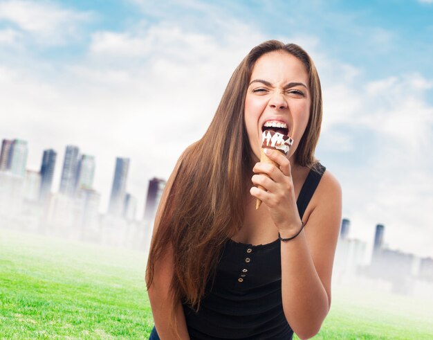 Retrato de muchacha que muerde un helado de chocolate.