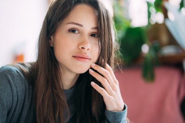 Retrato de la muchacha sonriente linda del inconformista que mira fijamente en cámara mientras que escribe ejercicios de la universidad en cuaderno.