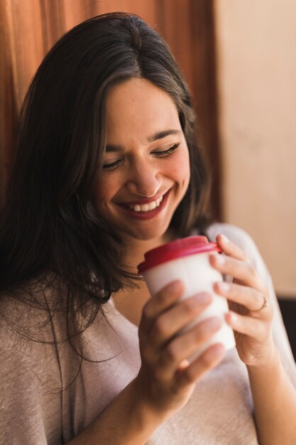 Retrato de una muchacha sonriente que sostiene la taza de café disponible