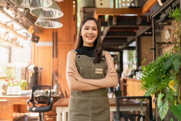 Retrato de mujer adulta asiática usar delantal de pie en la entrada de su taller de cerámica estudio incasual tela relajarse sonriendo confiada y cálida bienvenida mujer asiática con su taller de estudio en casa